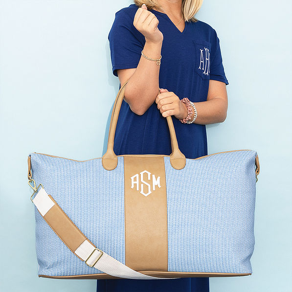 girl holding navy seersucker weekender on blue