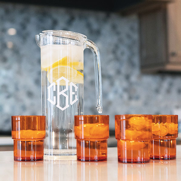 orange monogrammed acrylic pitcher with nesting cups on counter