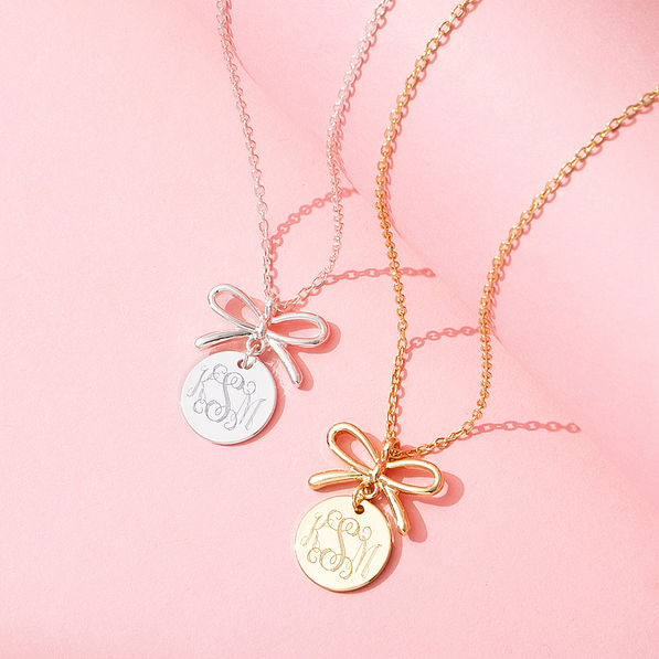 Gold and silver bow necklaces on pink