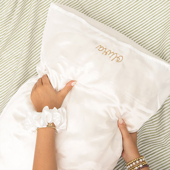 white satin pillowcase and scrunchie on green stripe sheets