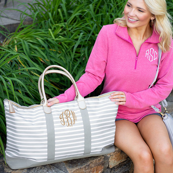 monogrammed gray striped travel bag with pink monogrammed pullover on wall