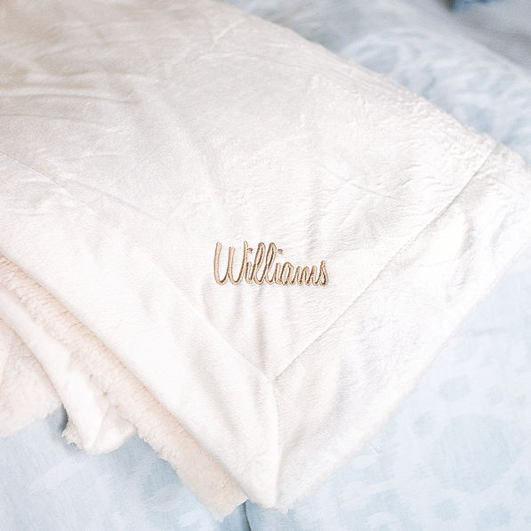 ivory monogrammed sherpa blanket on bed