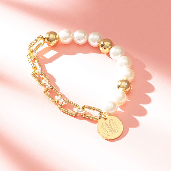 gold pearl bracelet on pink background with shadows