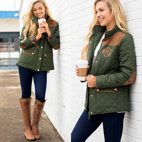 olive monogrammed barn coat on girl leaning on white brick wall