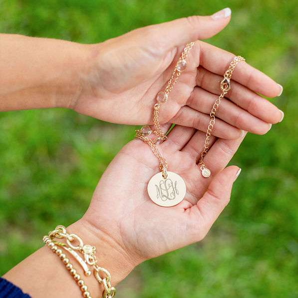 gold long pave necklace in hands near grass