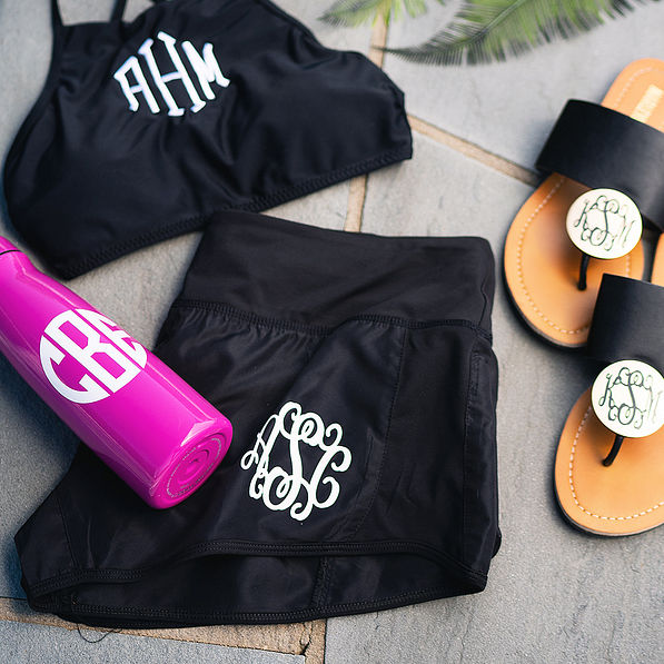 black monogrammed athleisure shorts with bikini top and sandals by pool