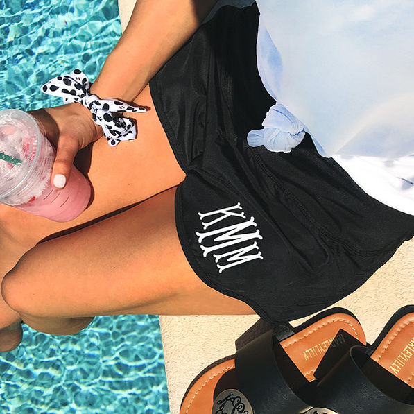girl sitting by the pool wearing monogrammed athleisure shorts holding starbucks smoothie