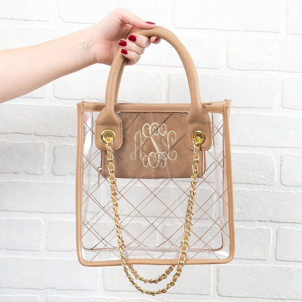 monogrammed clear tote in front of white brick wall