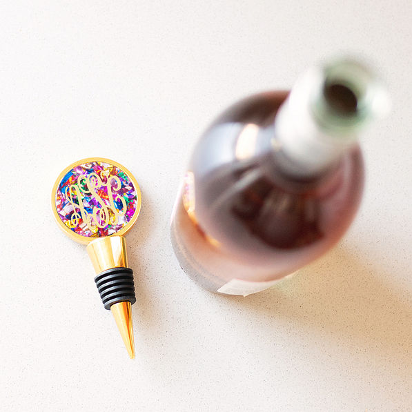 monogrammed confetti wine stopper beside open wine bottle