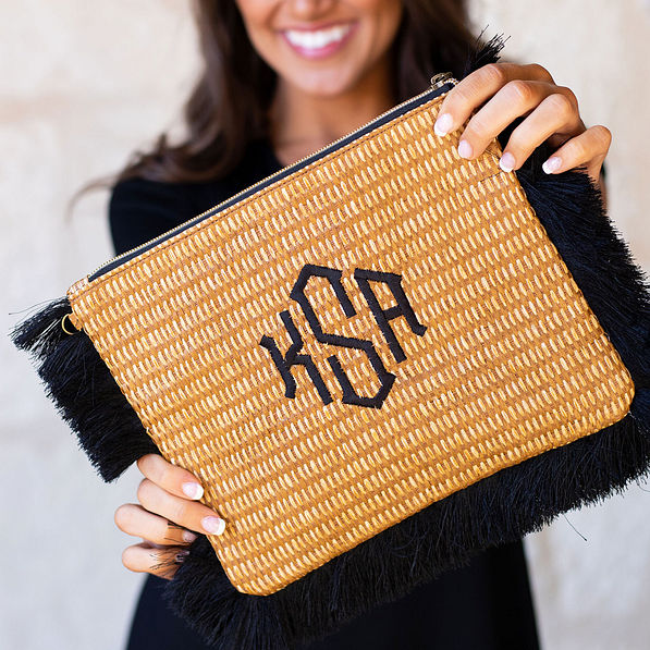 close up of monogrammed straw clutch with black fringe