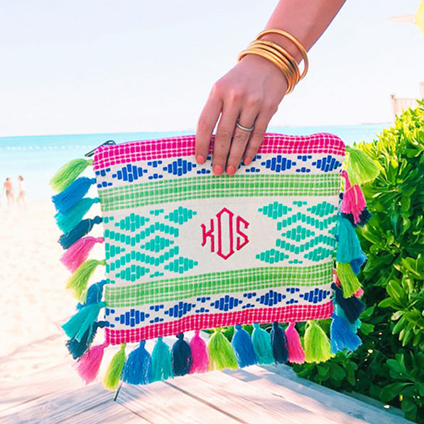 monogrammed tropical tassel clutch at beach with gold bracelets