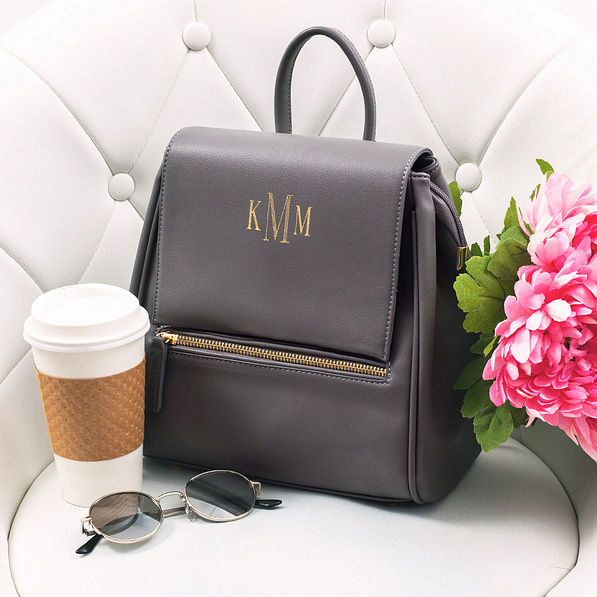 charcoal gray foil stamped mini backpack sitting in chair with flowers and coffee