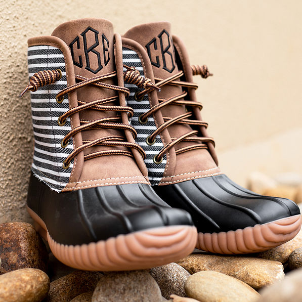 black striped monogrammed duck boots on rocks