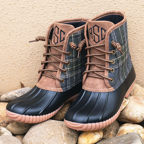 monogrammed plaid and black duck boots propped up on rocks