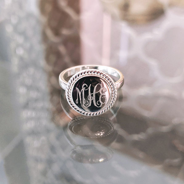 sterling silver monogrammed nala ring sitting on glass tabletop