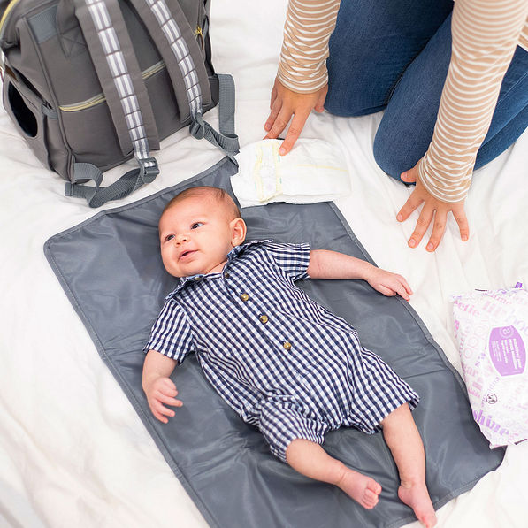 baby laying on diaper bag pad