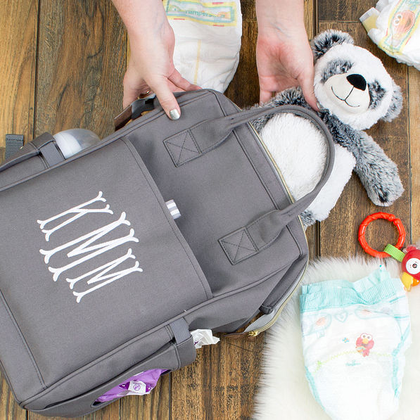 filling monogrammed gray diaper bag with stuffed animal panda