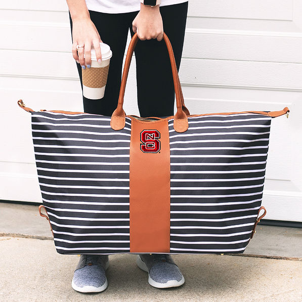 woman holding nc state striped weekender bag