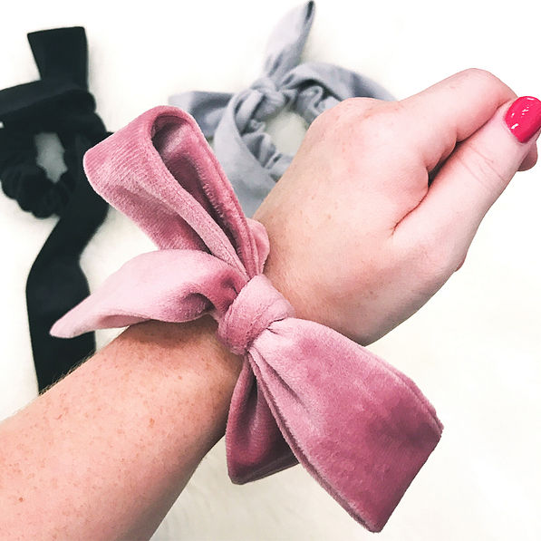 blush velvet bow scrunchie on wrist