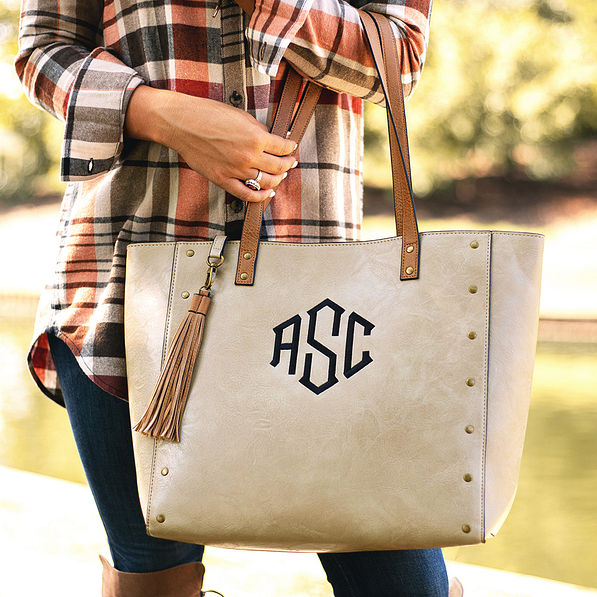 taupe monogrammed cheyenne tote on arm with tassel