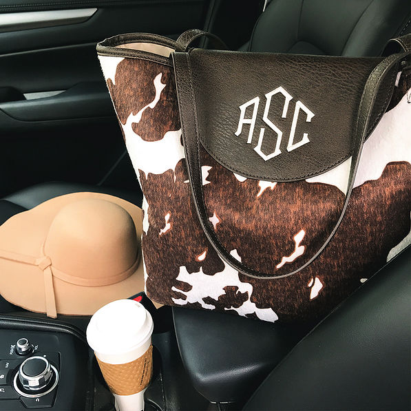 monogrammed cowhide tote in car with felt floppy hat