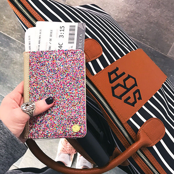 girl holding confetti passport cover with monogrammed carry on