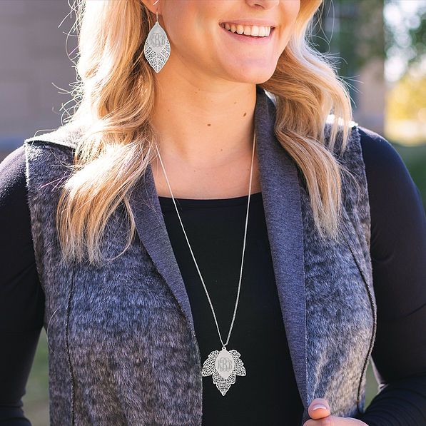 blonde wearing silver monogrammed leaf jewelry
