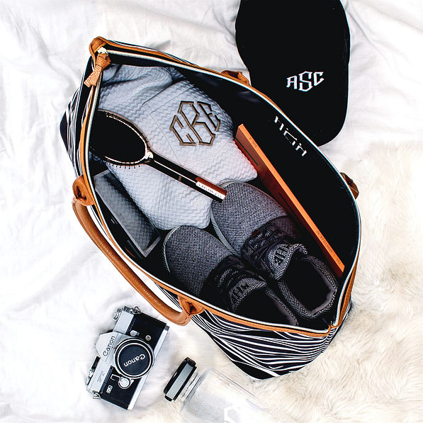 inside of monogrammed carry on bag with sneakers and hat