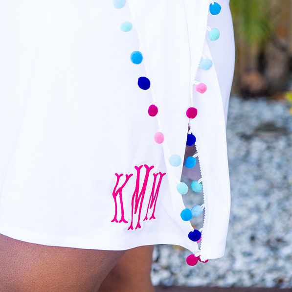 detail of monogrammed pom pom cover up in white