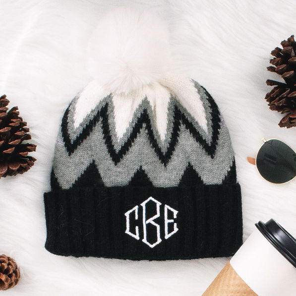 black and white pom pom beanie on white fur rug