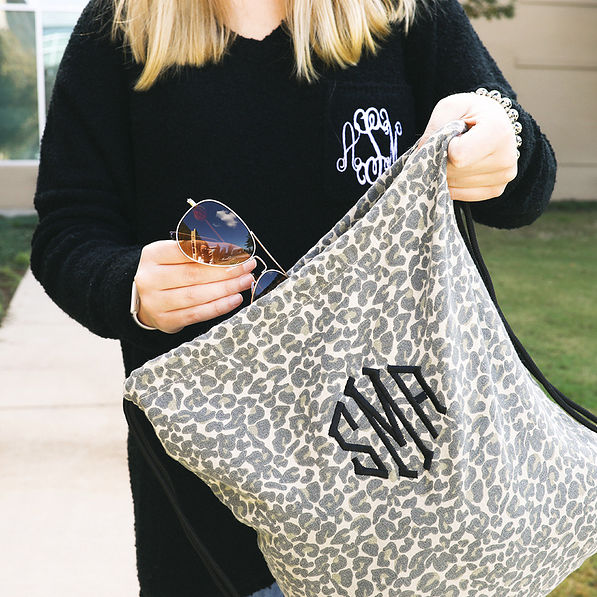 putting sunglasses inside of rustic leopard monogrammed cinch bag