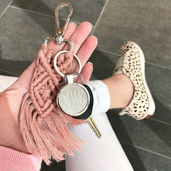 blush macrame keychain in hand with spotted sneakers