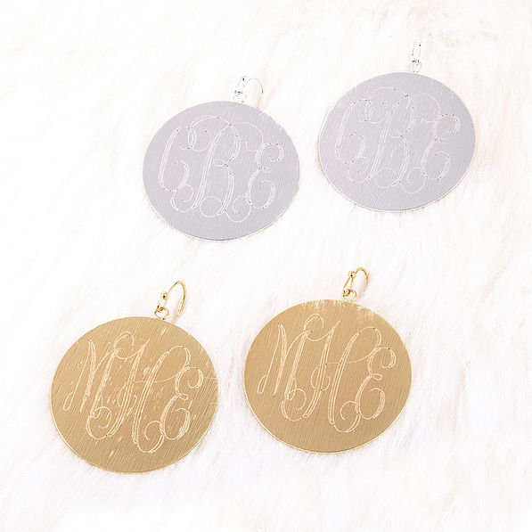 silver and gold monogrammed brushed earrings on fur
