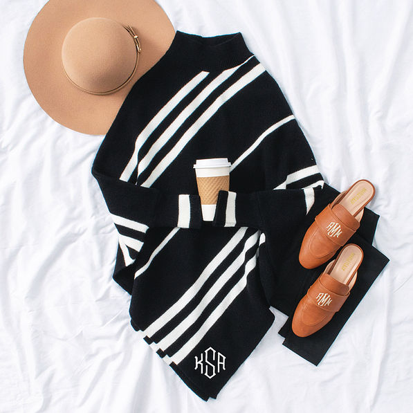 tan wide brim hat with black monogrammed sweater poncho