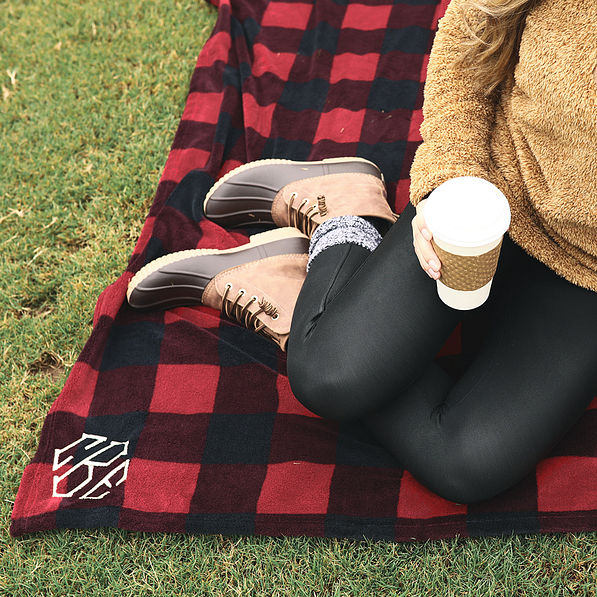 girl sitting on monogrammed buffalo plaid blanket outside