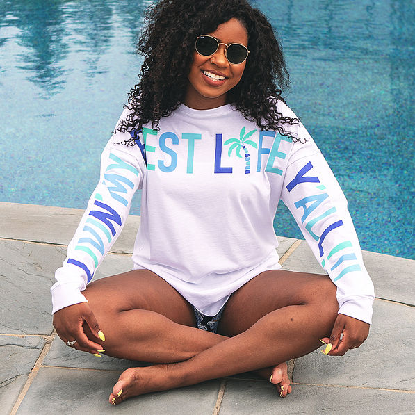 girl sitting by pool with living my best life t-shirt