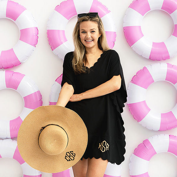 girl in black bathing suit cover and sun hat over pool rings