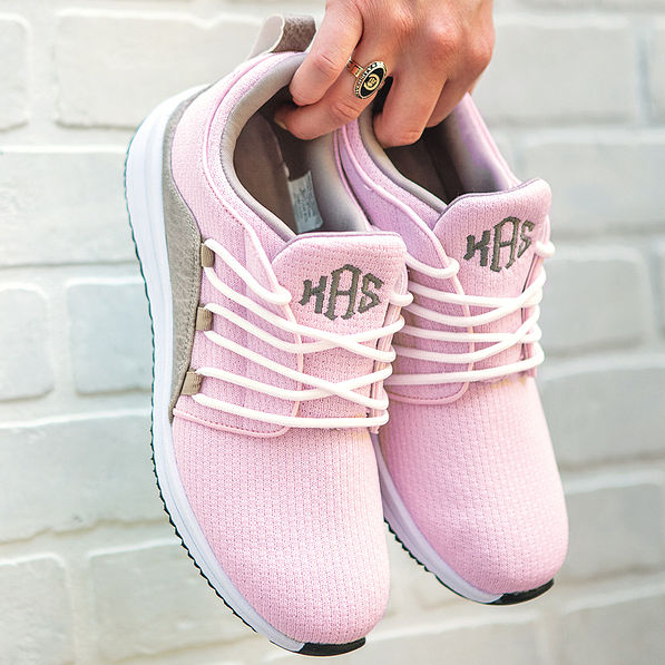 holding monogrammed pink athletic sneakers