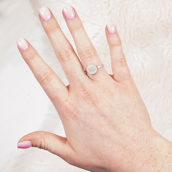 silver monogrammed audrey ring on hand in front of fuzzy rug