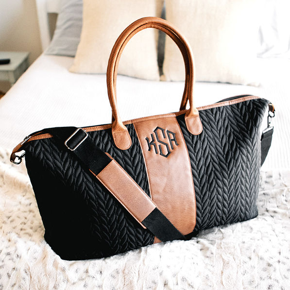 monogrammed black and brown quilted travel bag on bed