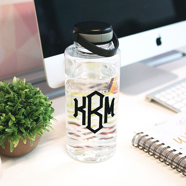 clear motivational water bottle with black monogram on desk