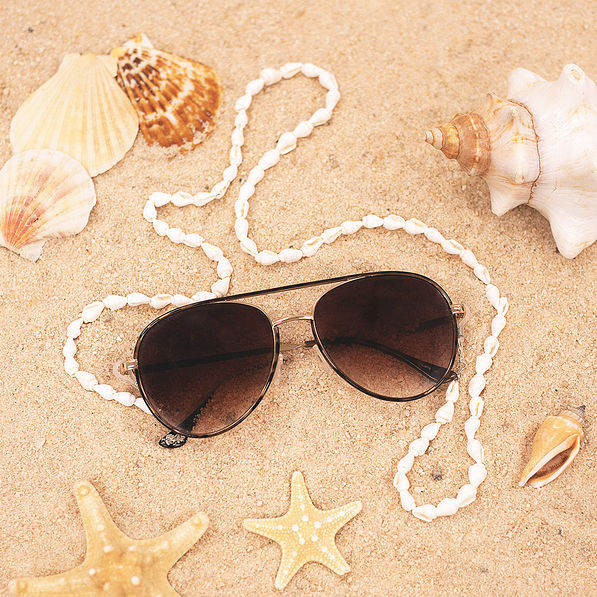 seashell sunglasses strap on aviator sunglasses laying in sand
