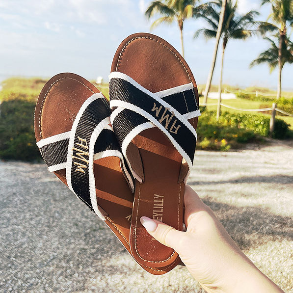 girl holding monogrammed criss cross sandals at the beach