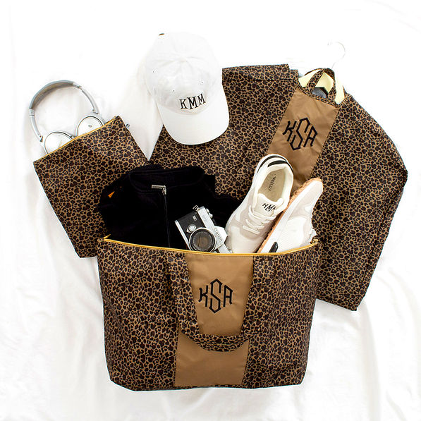 leopard packable garment bag and duffel on sheet