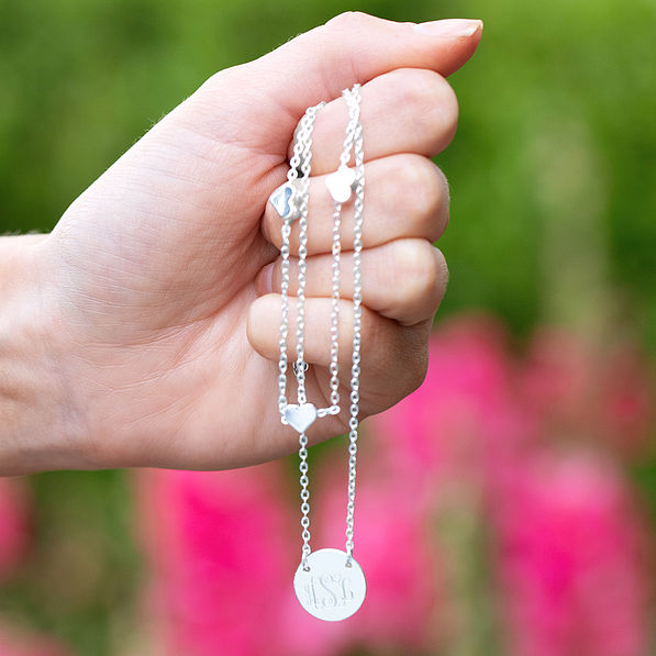 hand holding silver heart multistrand necklace in front of flowers