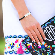 monogrammed black beaded bracelet in black holding clutch