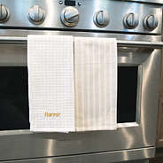 dish towel set in khaki with embroidered name hanging on stove