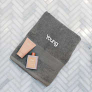 monogrammed bath towel in grey laying on tile floor with name new