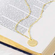 gold faith or fear necklace on book