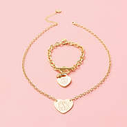 monogrammed heart bracelet and necklace in gold on pink